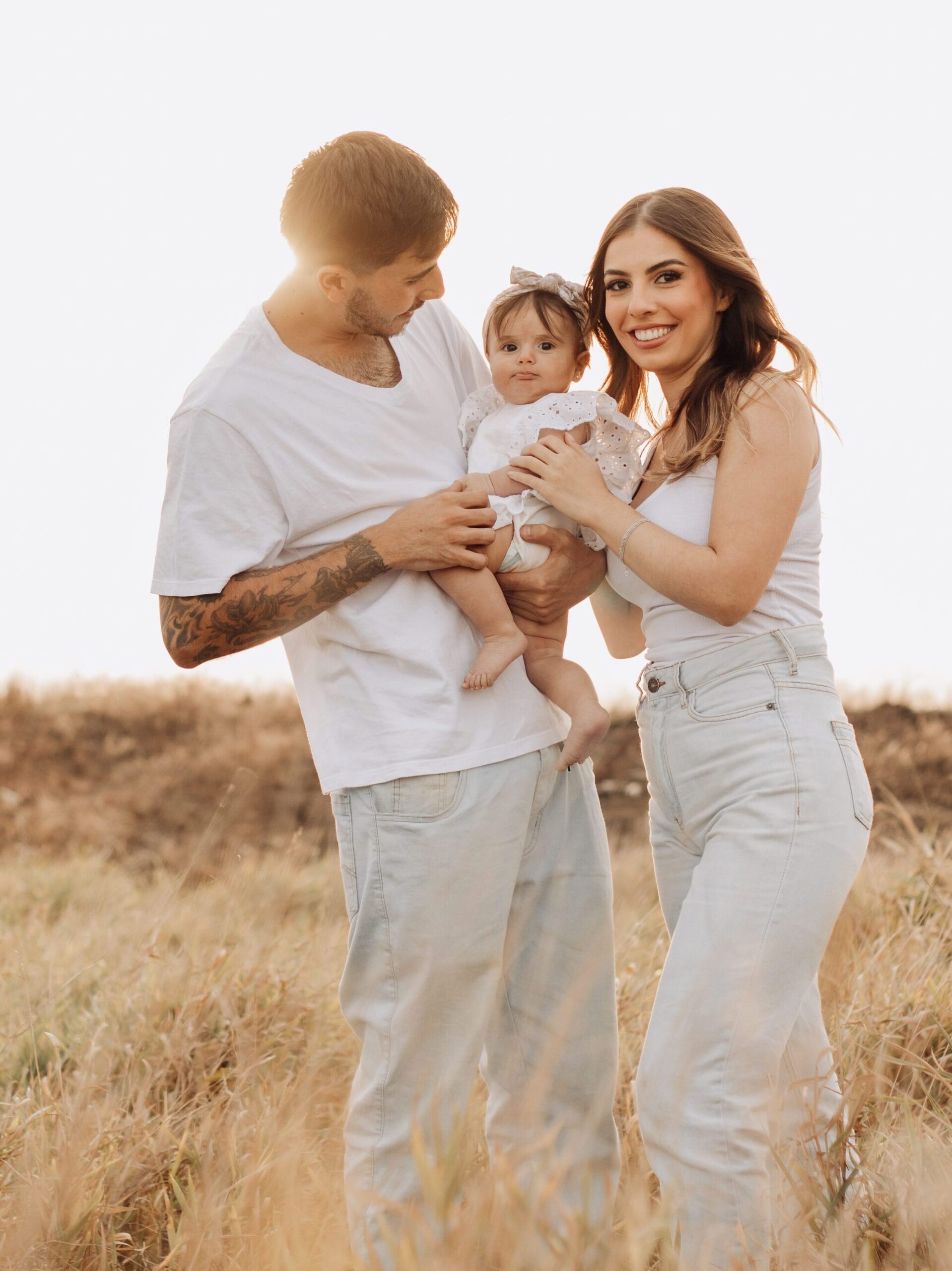 Home A joyful family of three enjoying their time in the sunny outdoors, displaying love and togetherness.